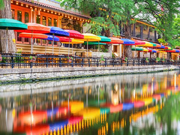 Colorful outdoor cafes with rainbow umbrellas along a calm waterway, reflections shimmering in the river.